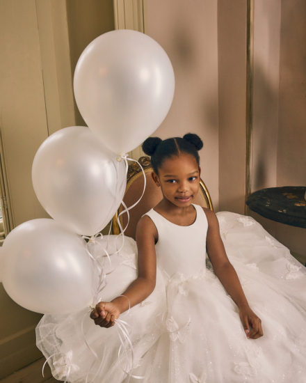 Kinderkleid mit voluminösem Tüllrock und Schmetterlingsdetails, inszeniert mit Luftballons